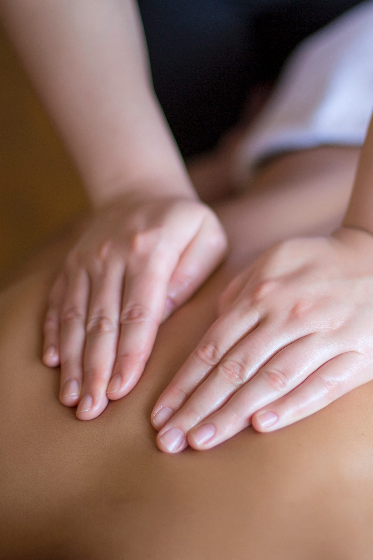 Deux mains massant le dos d’une personne allongée